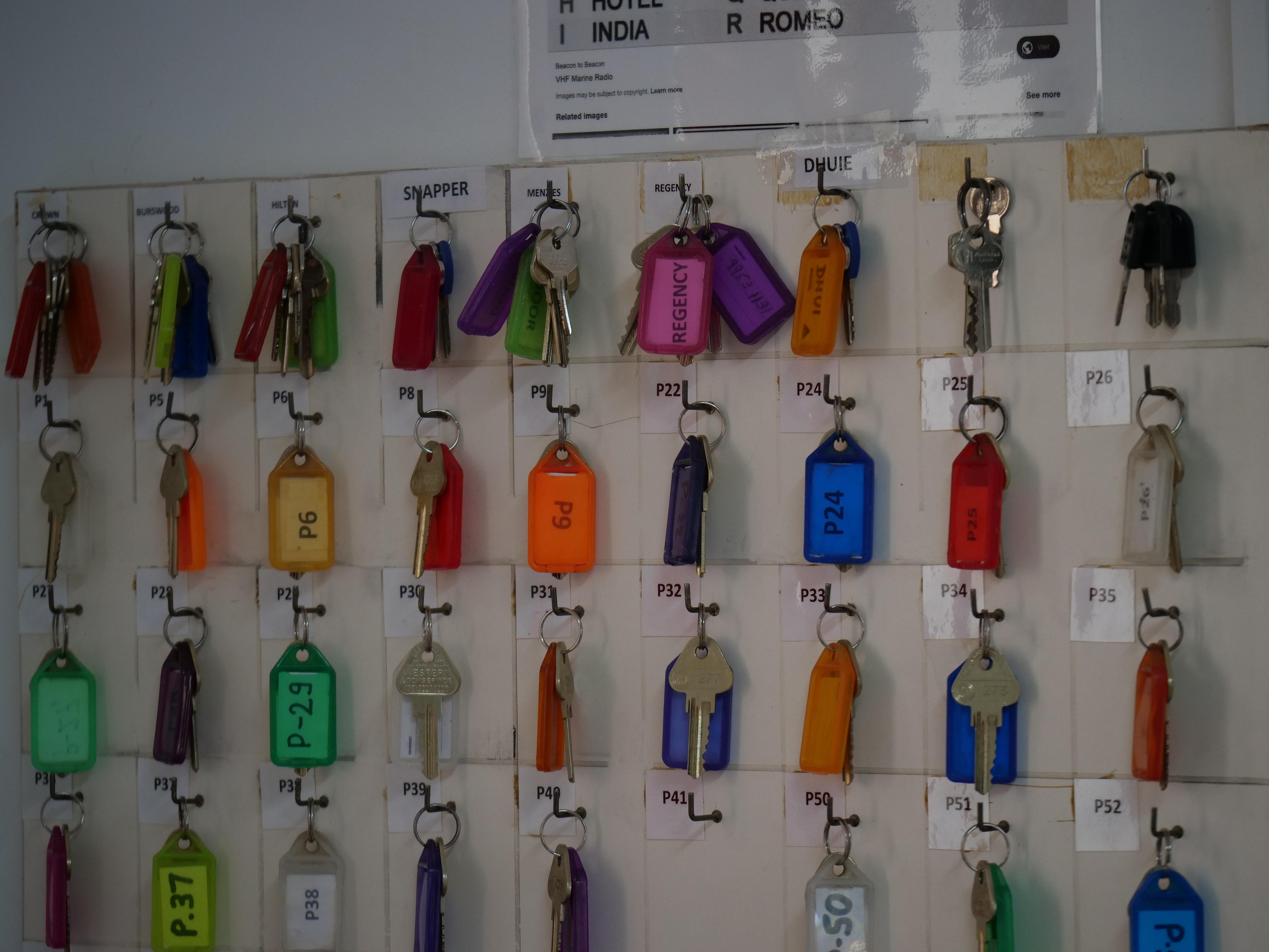 De sus ganchos cuelgan hileras de llaves con diferentes números. 