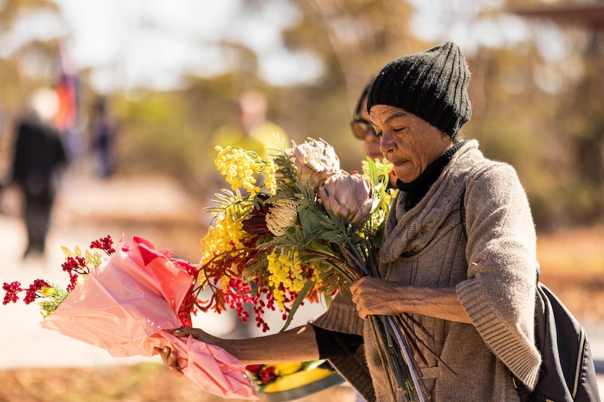 A woman holding flowers at a memorial service for fallen police officers.   