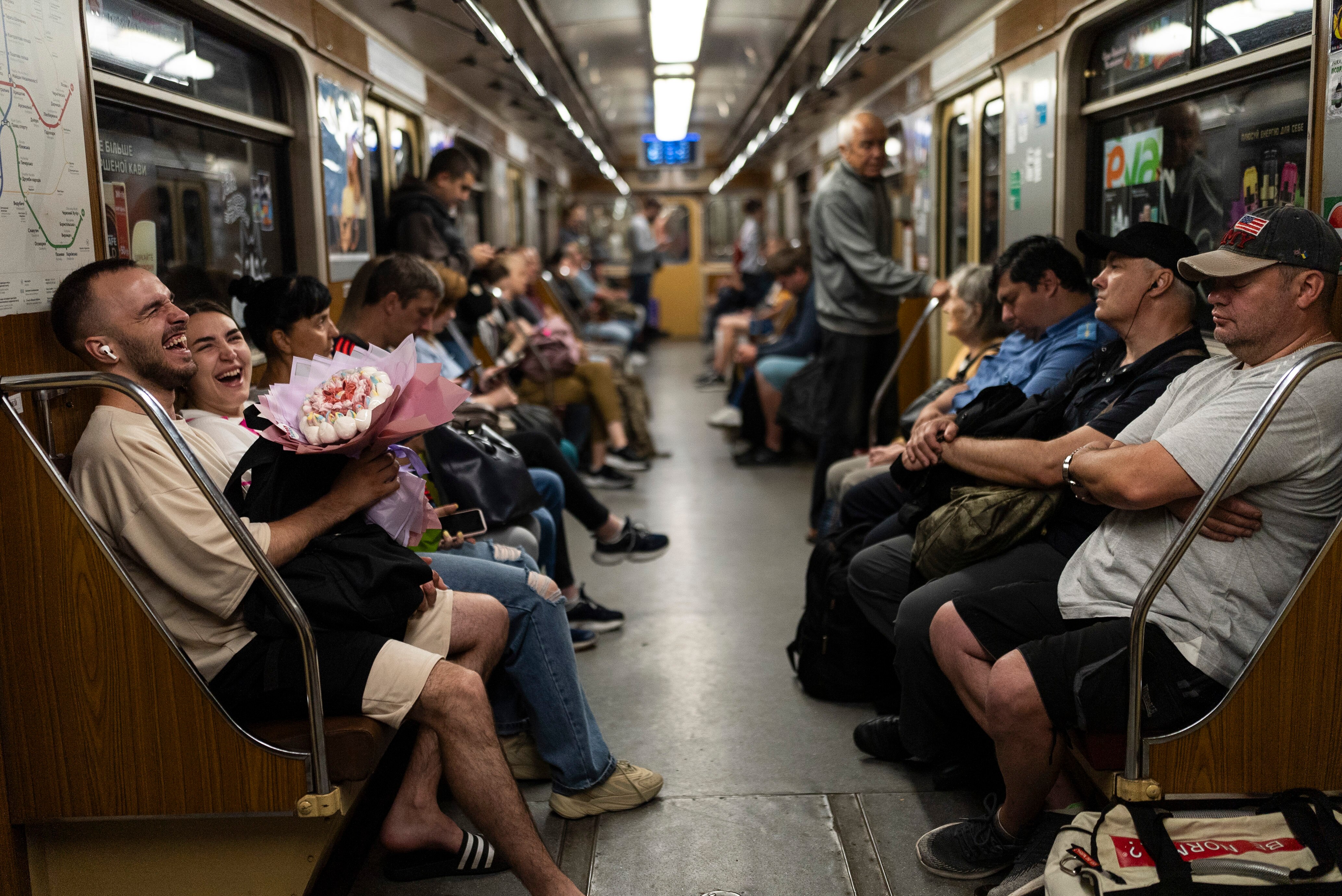 A subway car full of people, on the front left a young couple is laughing