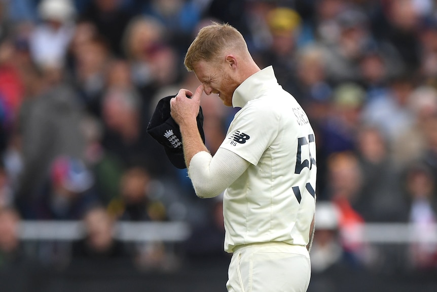 Ben Stokes pinches his nose and grimaces while looking down