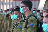 ADF officers lined up on arriving in Melbourne wearing blue surgical masks.
