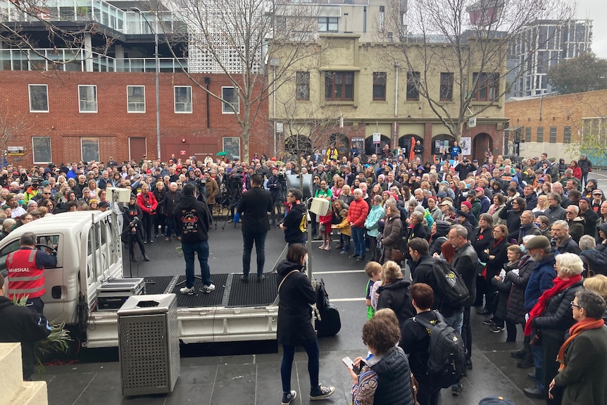 Crowds face a stage outside Trades Hall in Melbourne where speeches are delivered at the Come Together For Yes rally