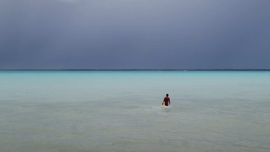 A turquoise lagoon with a person wading out