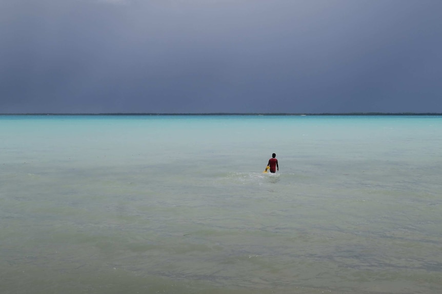 A turquoise lagoon with a person wading out