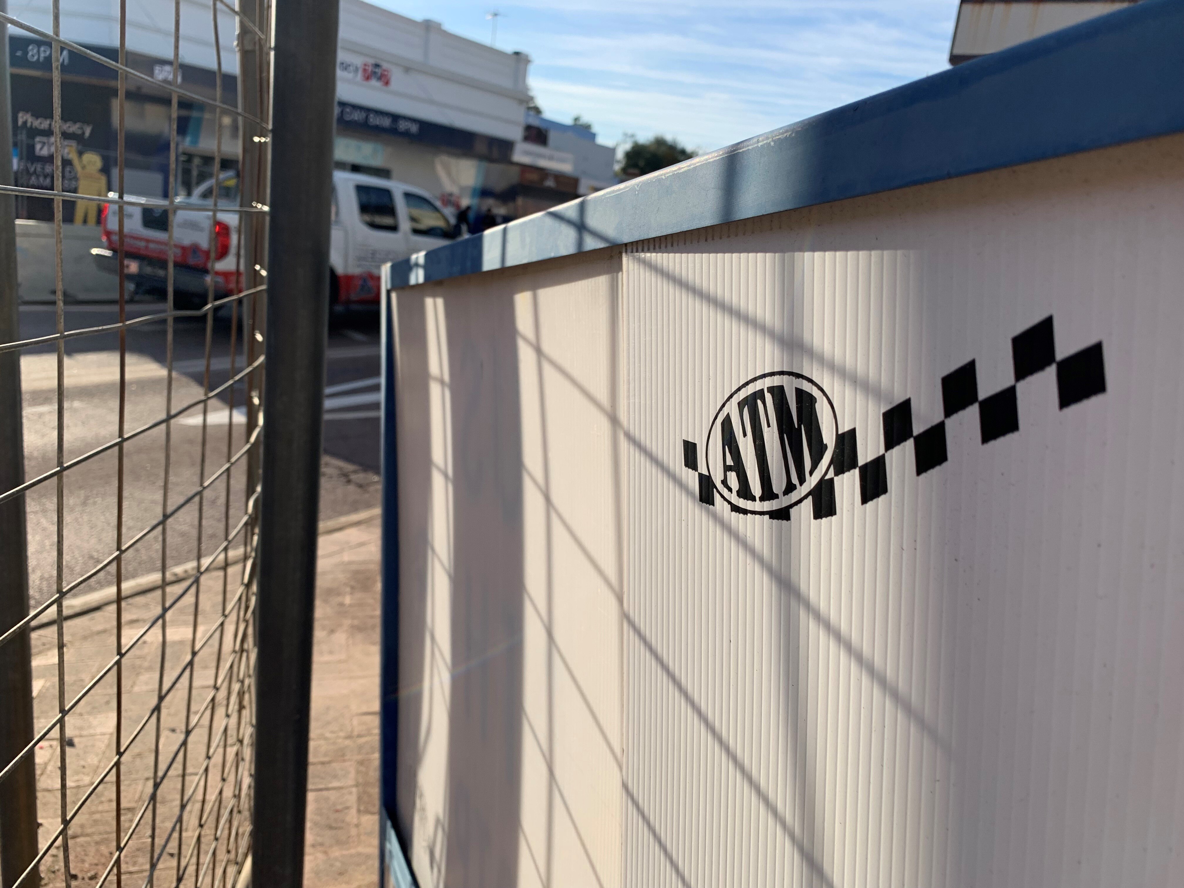 A close-up of the Australian Traffic Management logo on fencing at a road construction project with a car in the background.