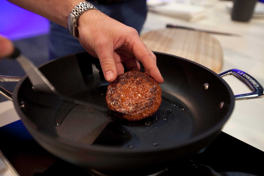 Cooking a cultivated beef patty in a frypan.