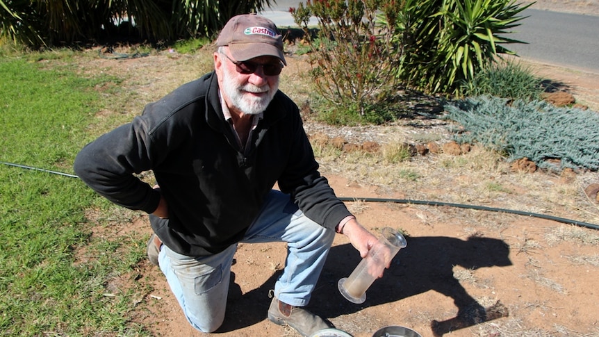 A farmer checking an empty rain gauge