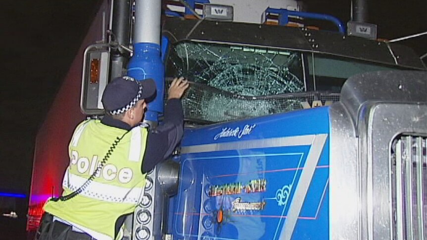 Police officer examines windscreen of damaged truck