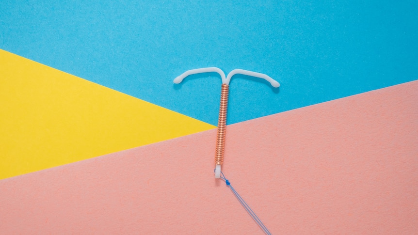 A white intrauterine device on a colourful background.