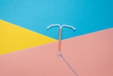 A white intrauterine device on a colourful background.