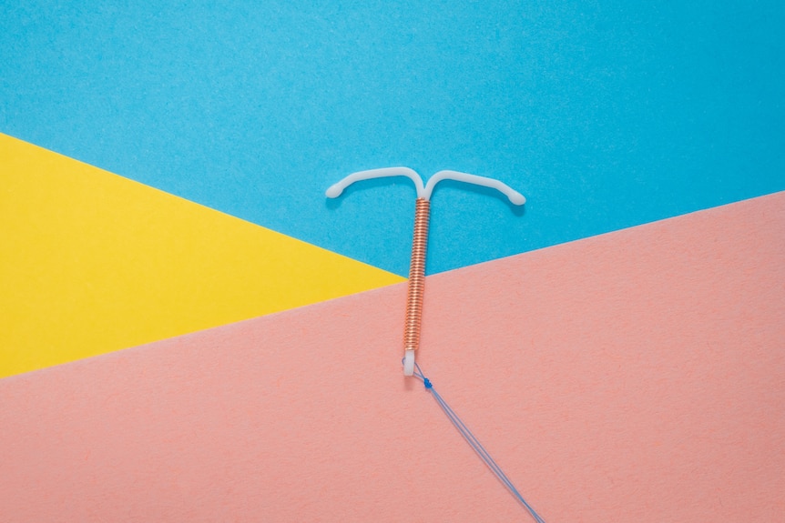 A white intrauterine device on a colourful background.