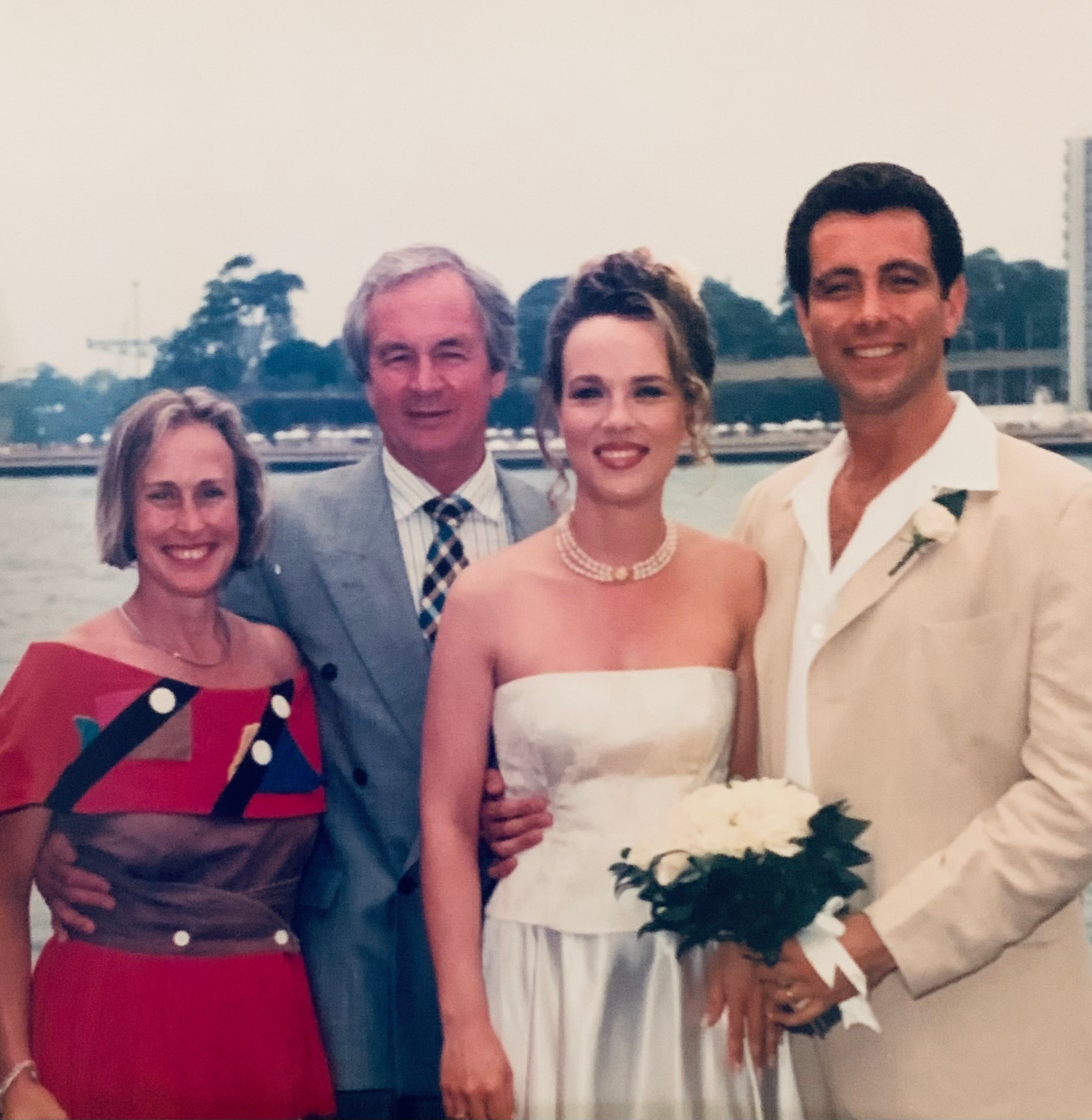 Uma foto de casamento com um casal mais velho ao lado de um casal mais jovem em ternos de casamento.