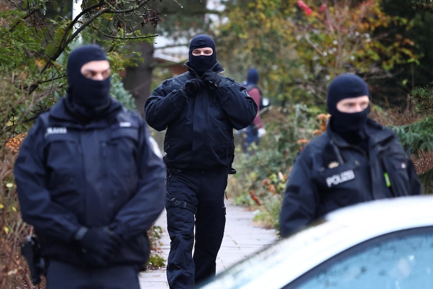 Police in tactical gear and balaclavas. 