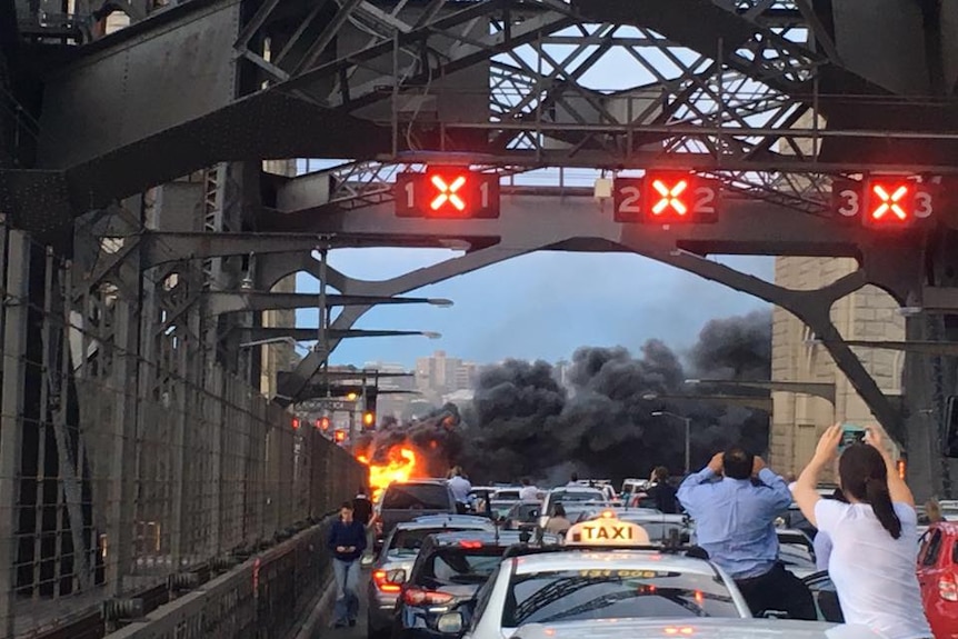 Drivers stop to watch a burning bus.