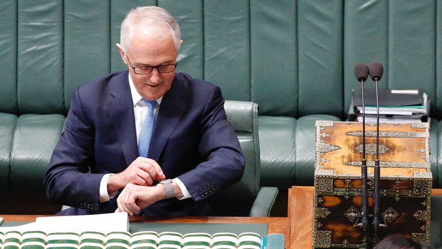 Malcolm Turnbull glances down to his left wrist and adjusts his watch with his right hand.