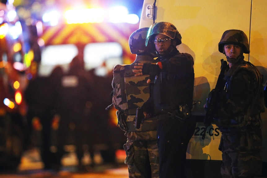 Security forces signal journalists to move back as they secure the area near the Bataclan concert hall