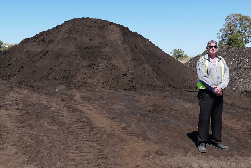 Tony Battersby stands next to a big pile of compost