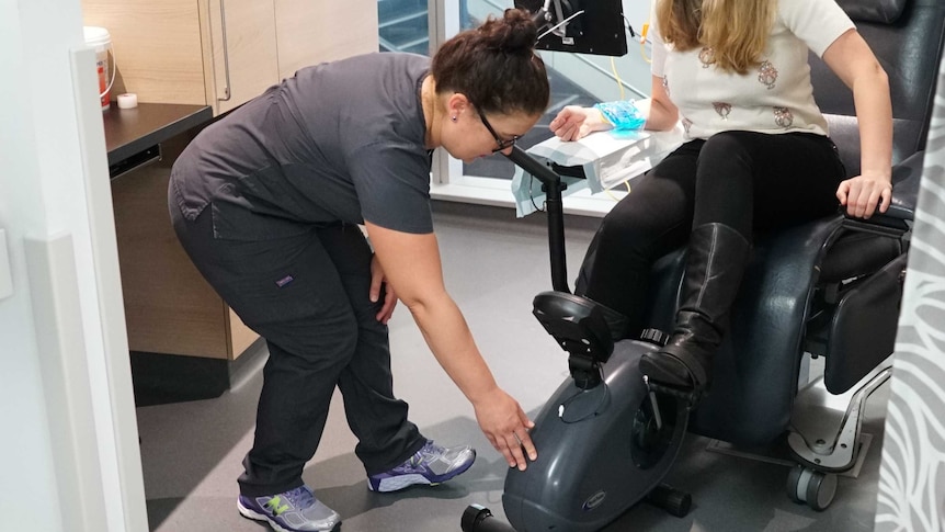 A woman demonstrates how a chemo patient would exercise during chemo treatment as part of a research trial.