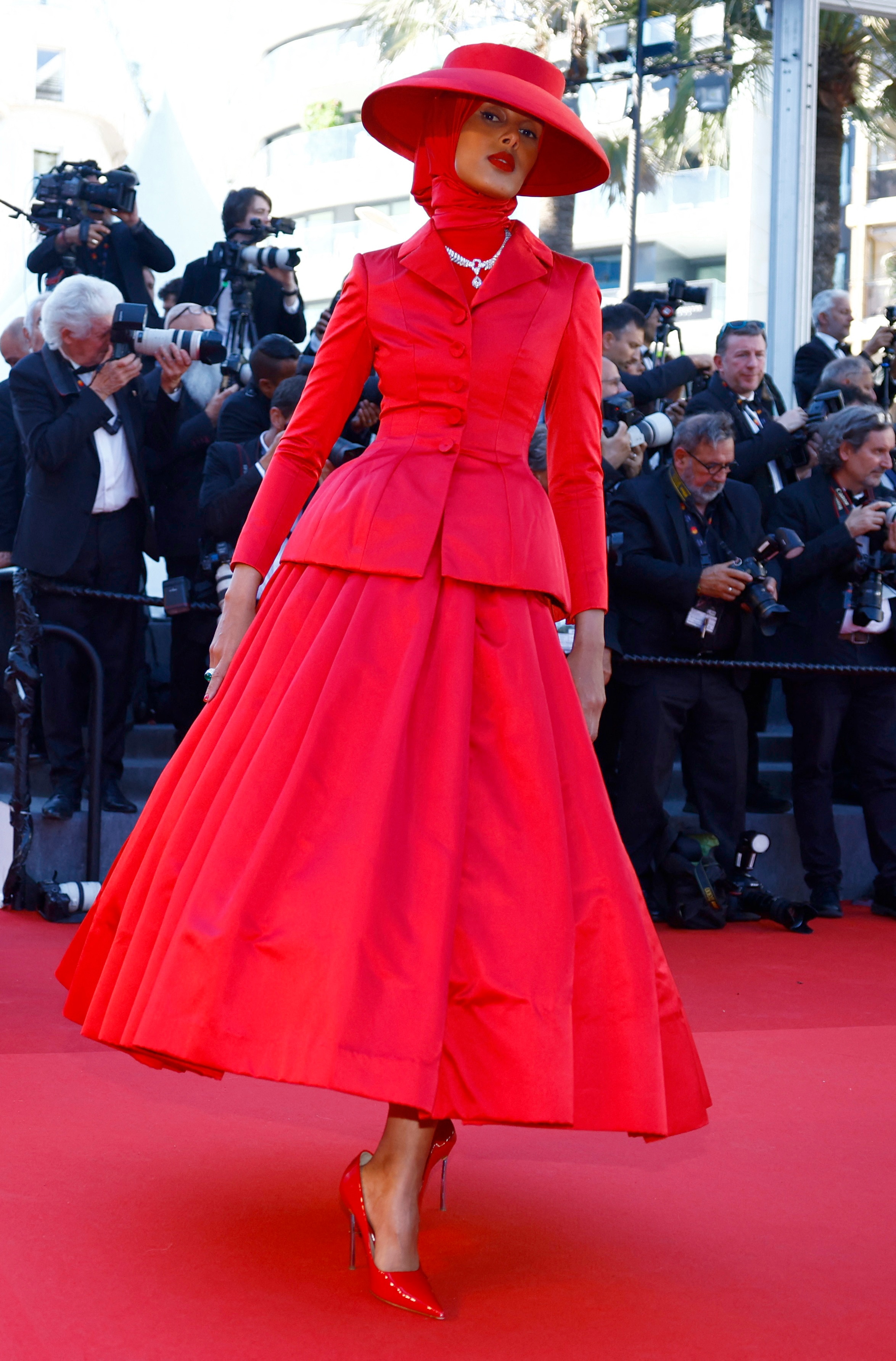 Rawdah Mohamed wearing a bright red A-line skirt, blazer, headscarf and wide-brimmed hat all in the same shade of red