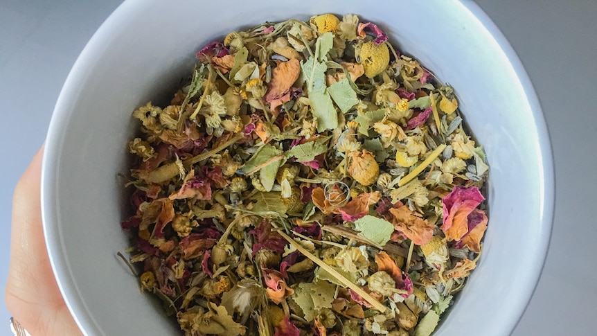 Dried colourful herbs and leaves in a cup of herbal tea.