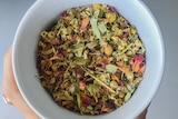 Dried colourful herbs and leaves in a cup of herbal tea.