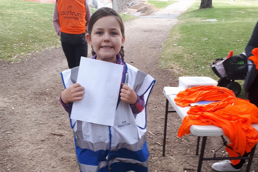 Isobel McKeown holds up a piece of paper at parkrun.