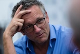 A close up of Dr Michael Mosley talking while leaning his head on his right hand.