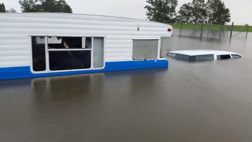 A car and caravan submerged in flood water.