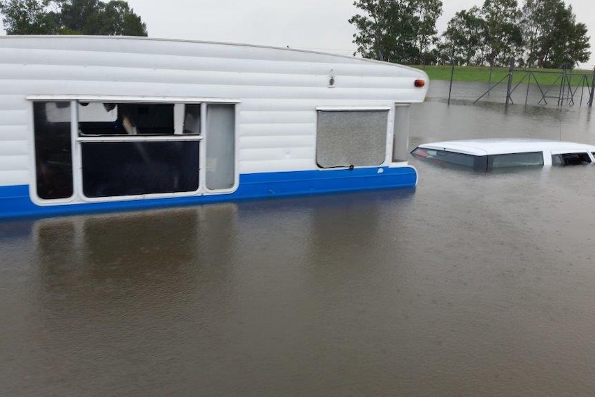 A car and caravan submerged in flood water.