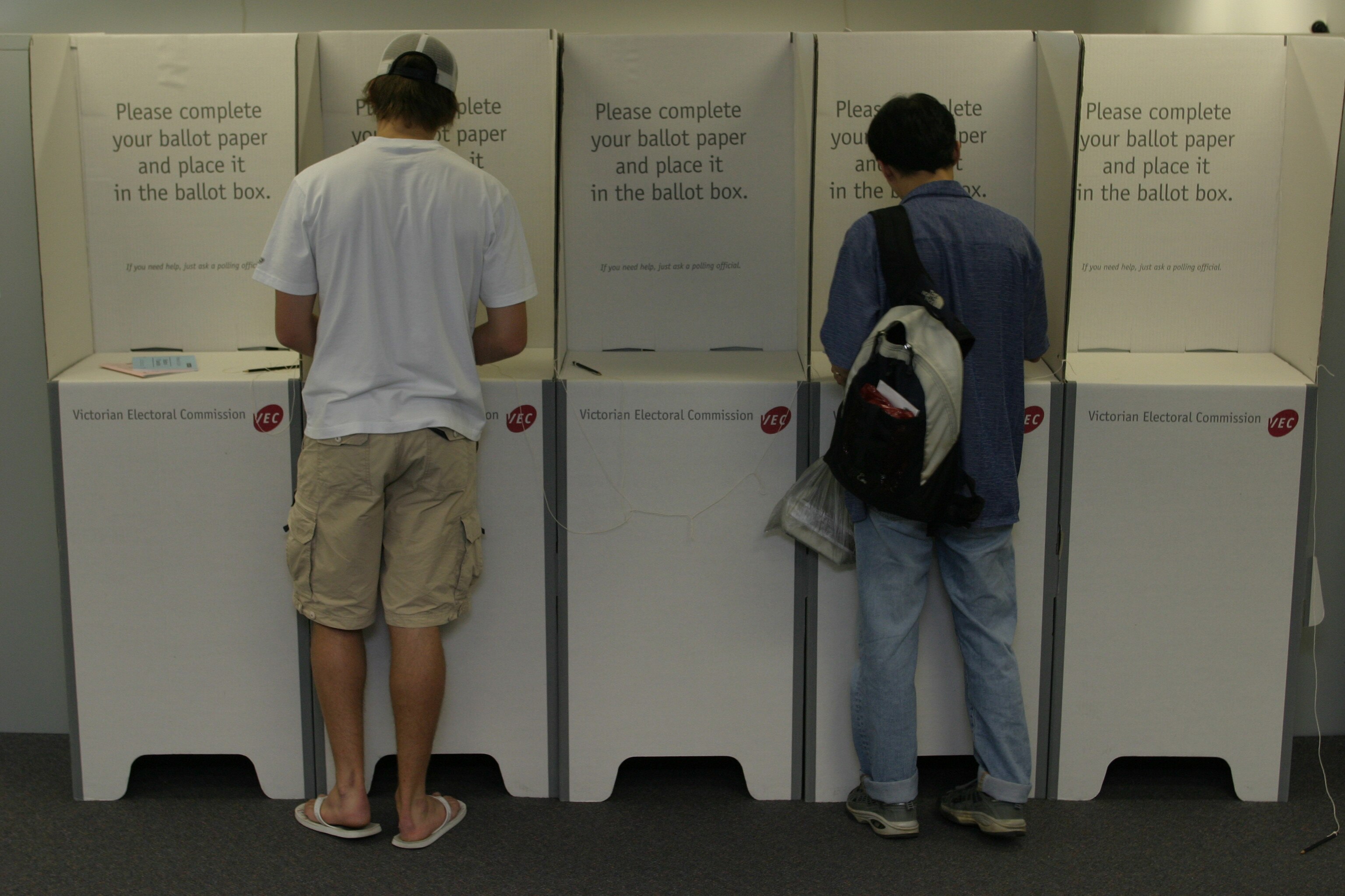 一个穿着白色衬衫和一个蓝色衬衫的在投票箱前投票