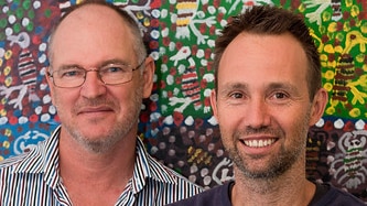 Mark Grose (right) and Michael Hohnen (left) standing in front of an Indigenous painting.