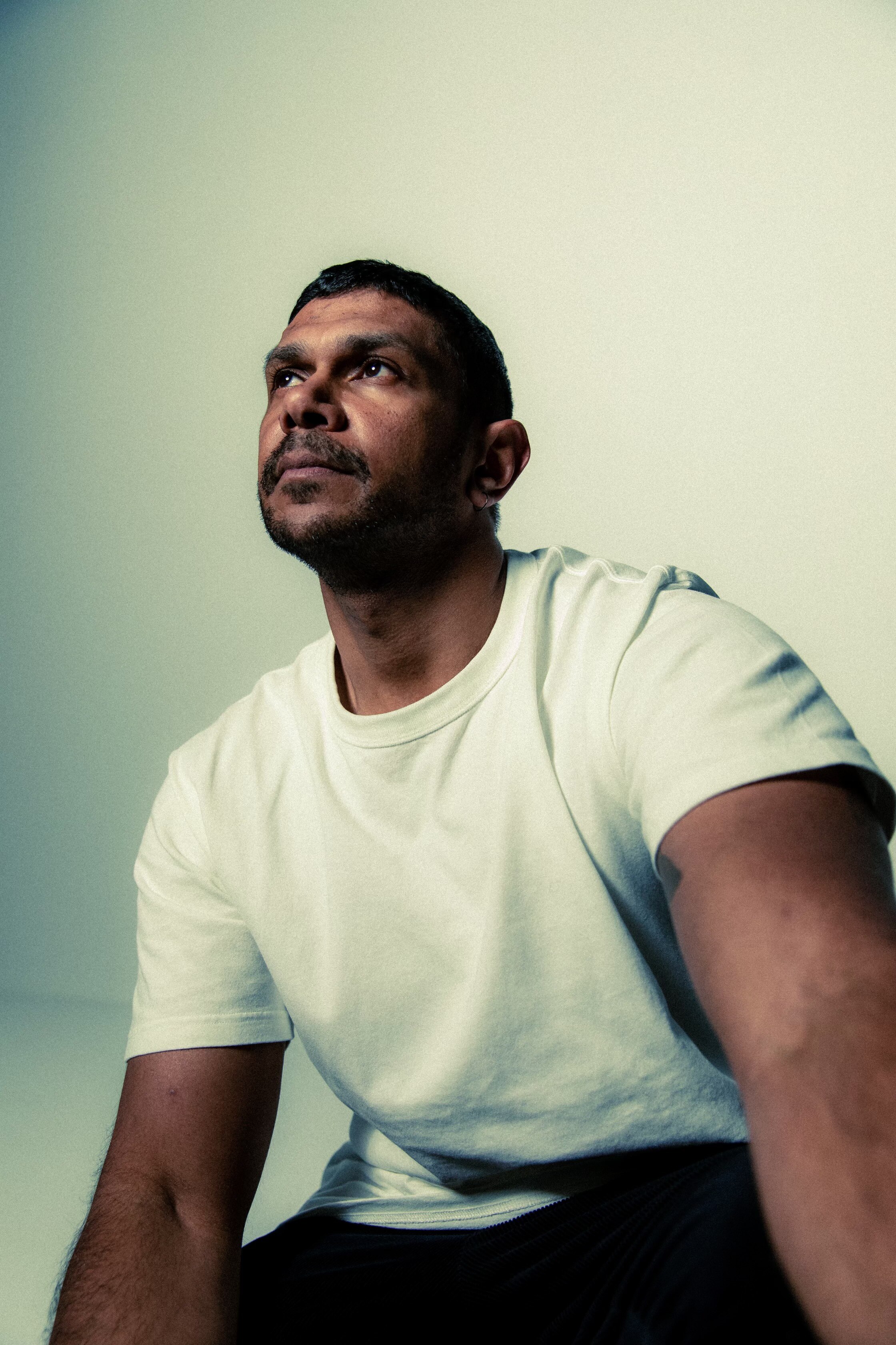 Maanyuing wearing a white t-shirt and looking thoughtfully into the top, left corner of the frame.