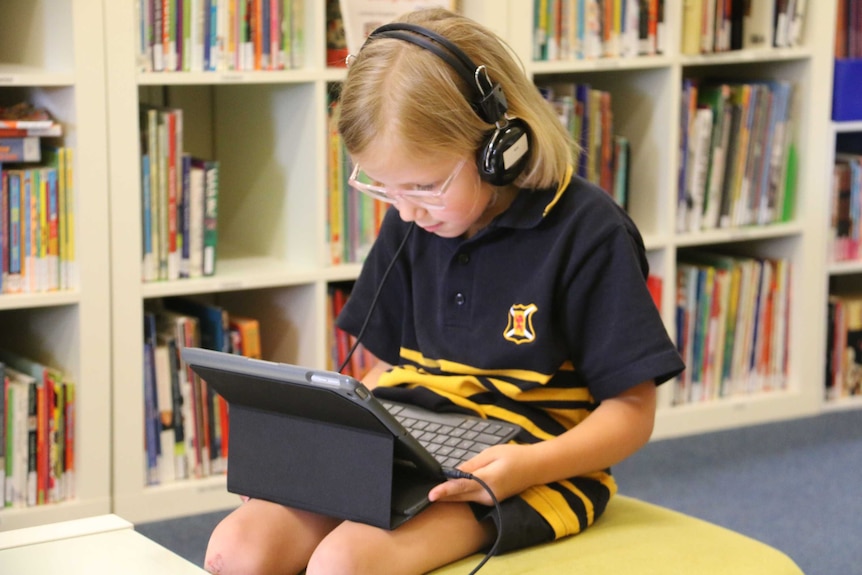 Primary school student use laptops in the library.