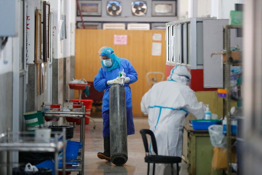 A Nepalese health worker in protective gear drags oxygen cylinder inside a COVID-19 ward.