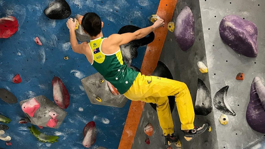 Angie Scarth-Johnson bouldering in green and gold.