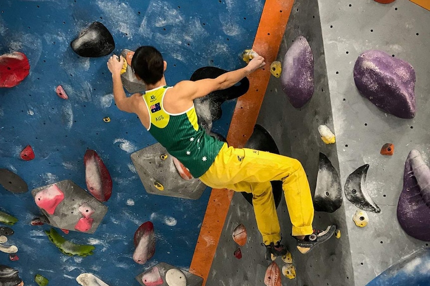 Angie Scarth-Johnson bouldering in green and gold.