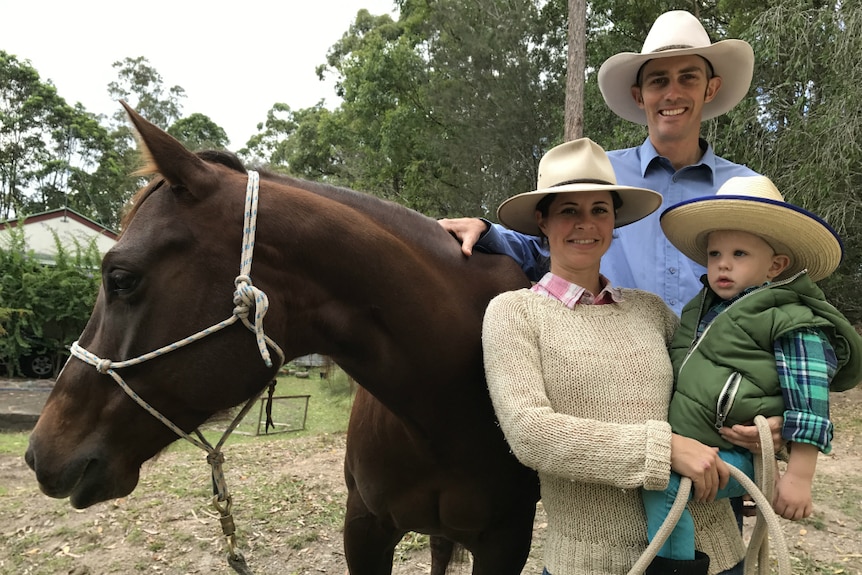 Ben and Linda Skerrett smile at the camera, holding their son and Amber the horse.  Everyone but the horse is wearing a hat.