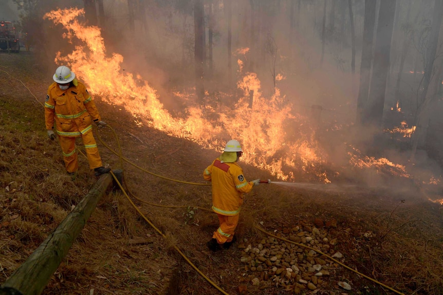 RFS volunteers conduct property protection as a bushfire comes within metres of homes west of Sydney.