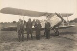 Four men standing in front of an old aircraft.