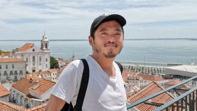 A man leans against a railing in front of a city view.