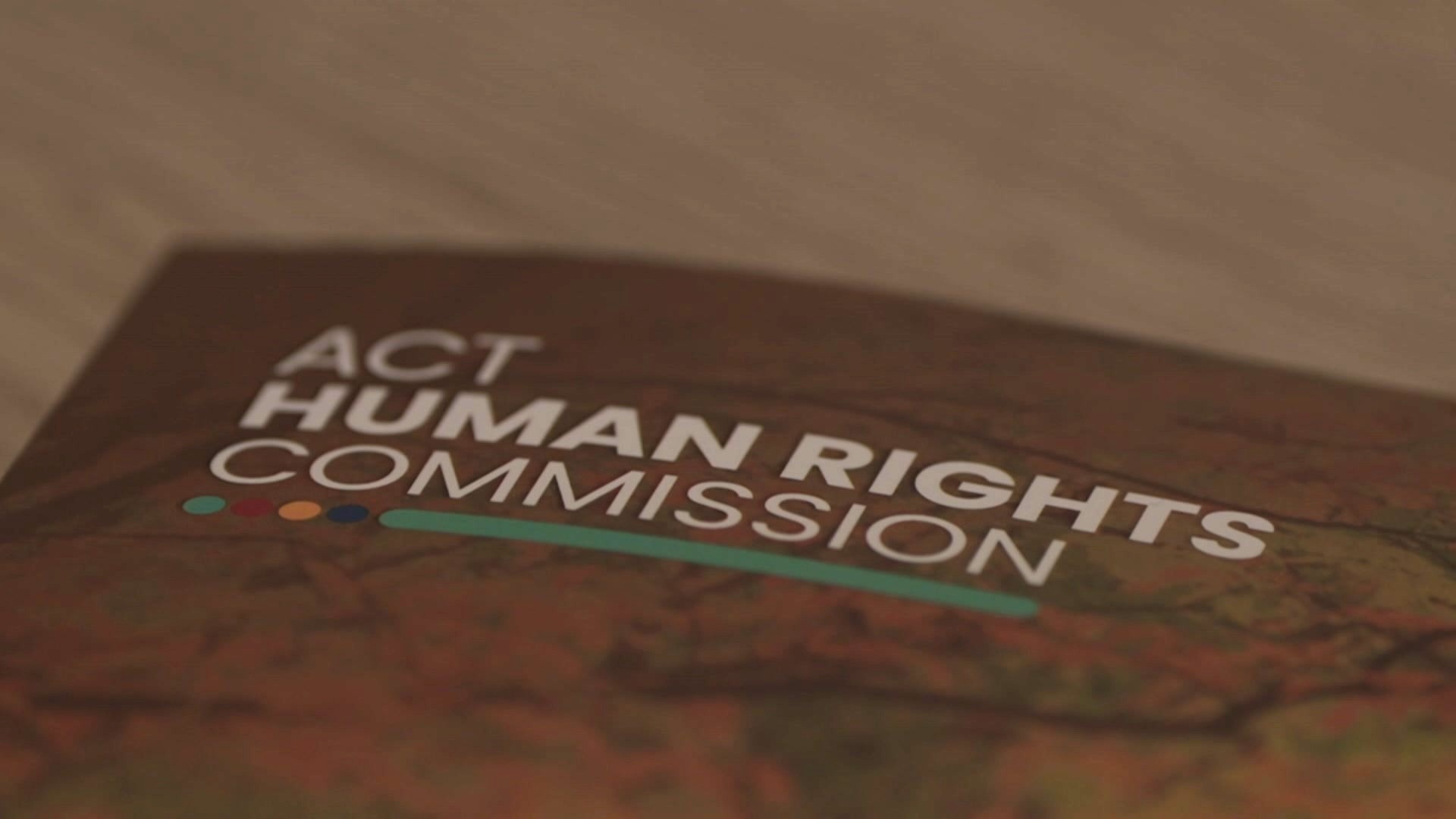 A close-up view of a bound report that reads "ACT Human Rights Commission" sitting on a table.
