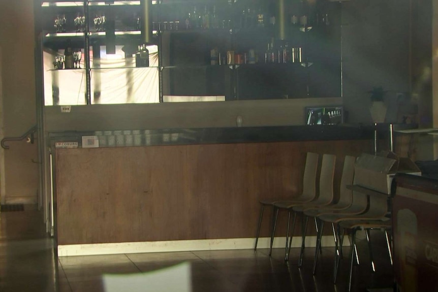 Looking through a window into a bar with a line of chairs along a wall.