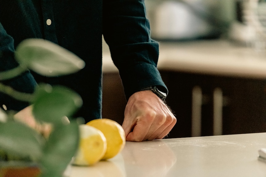 A close up of some lemons on a bench next to a man's hand.