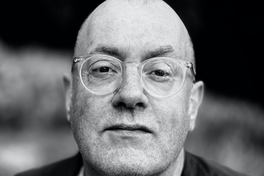 Black and white photo of a middle-aged bald man with glasses