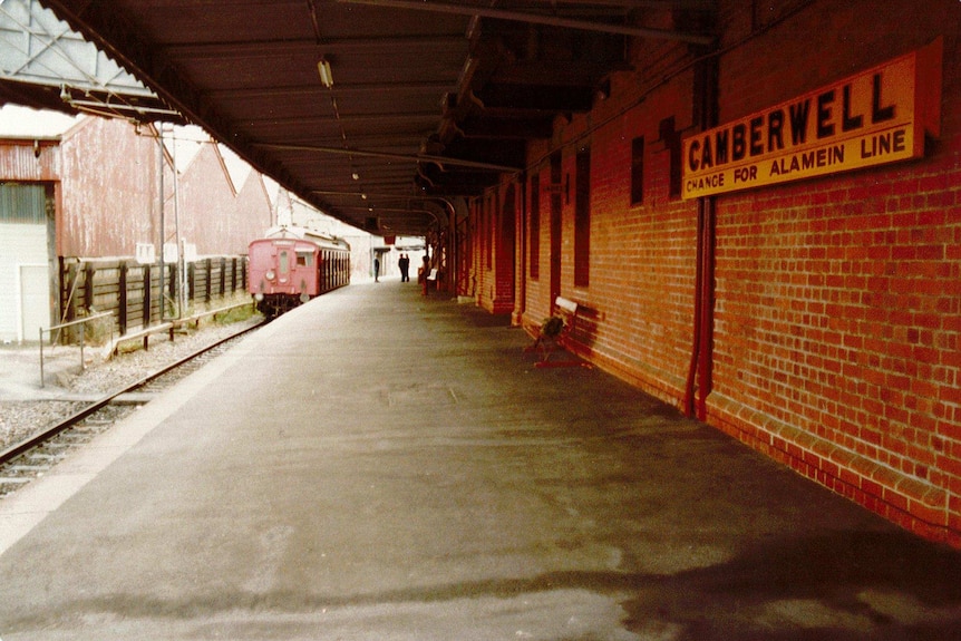 An empty train platform bar rail workers standing next to red one-car train