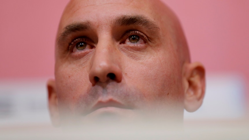 Luis Rubiales, a bald man, looks over the top and beyond the frame of the image. 