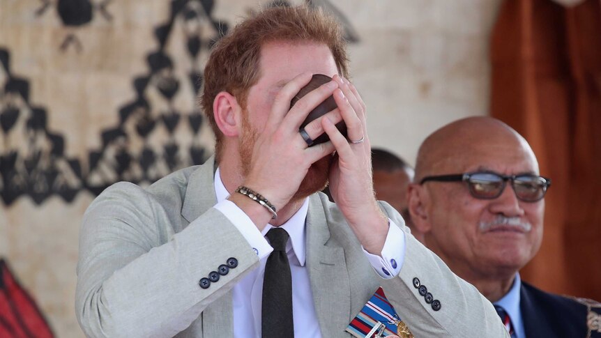 Prince Harry cups a coconut cup to his face and slurps kava.