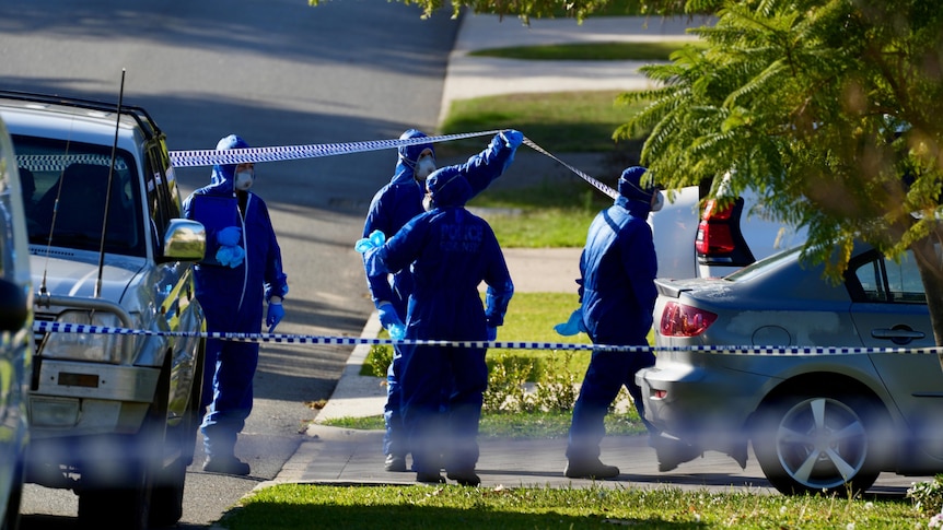 A group of forensics police officers wearing blue overalls outside a home on a suburban street.
