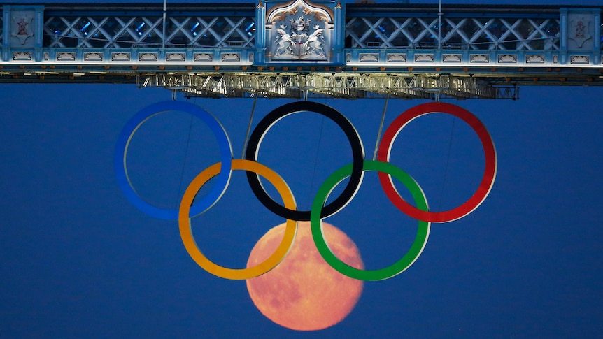 The full moon rises through the Olympic Rings hanging beneath Tower Bridge during the London 2012 Olympic Games August 3, 2012.