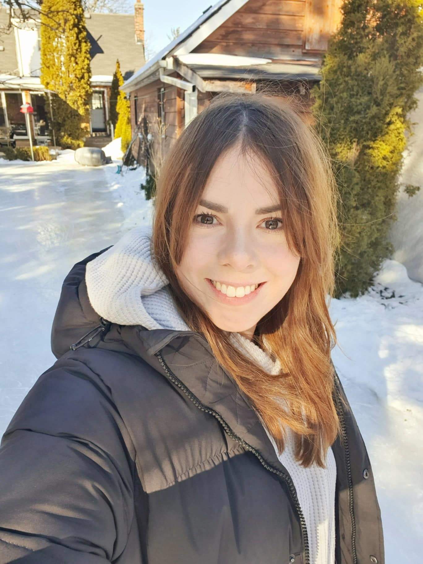 A young woman in front of a house covered in snow